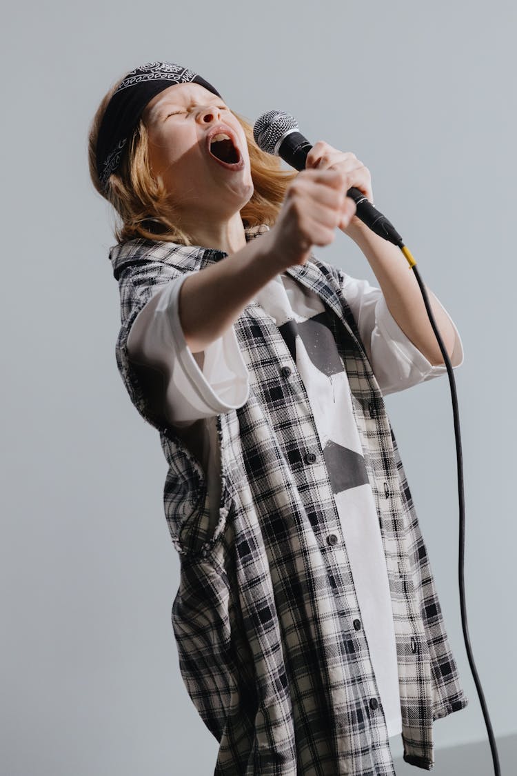 Photo Of A Kid Using A Microphone While Singing