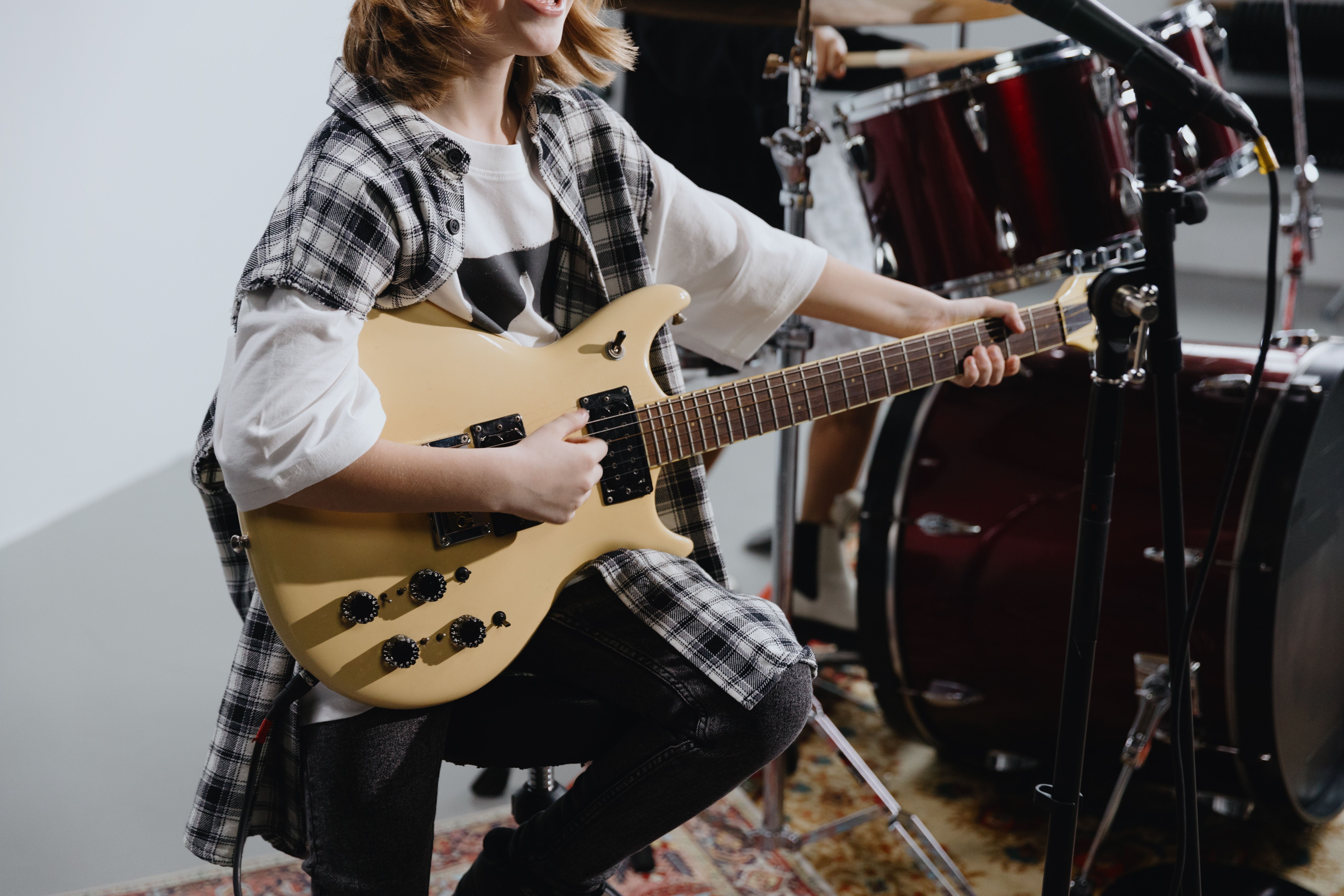 Young musician playing electric guitar in a studio setting. Inspiring musical talent.