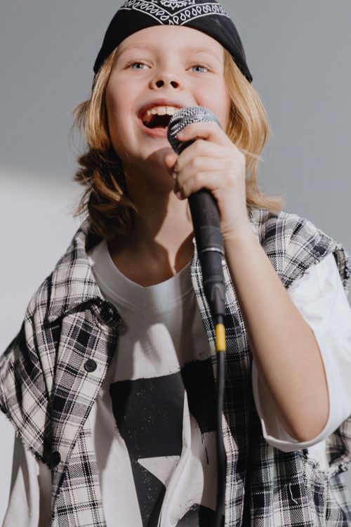 Free Joyful young girl in bandana passionately singing into a microphone. Stock Photo