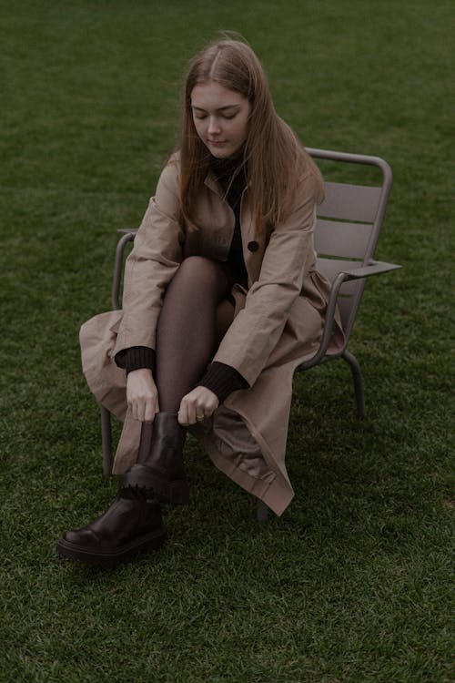 Photo of a Woman in a Brown Coat Putting on Her Boots