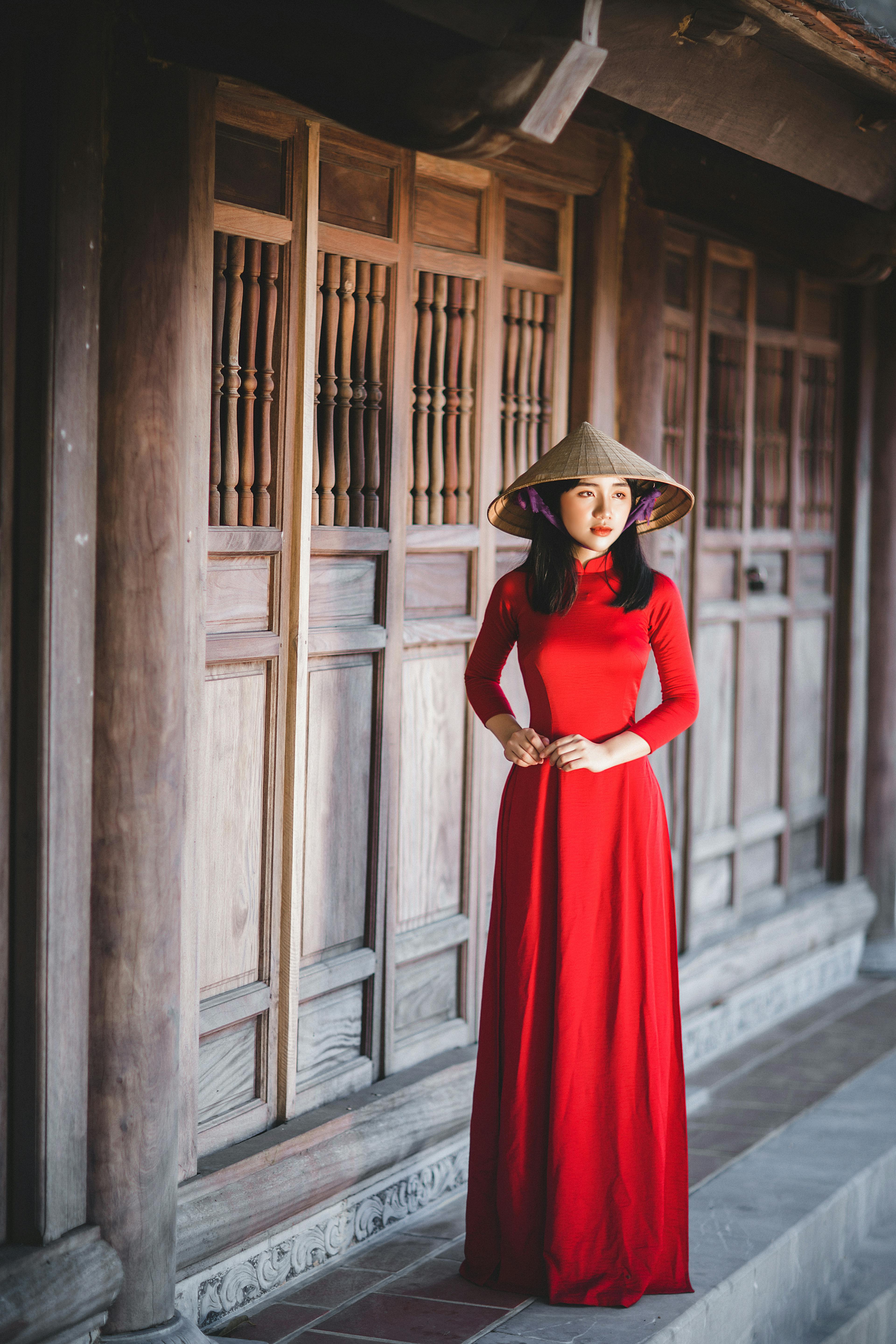 photo of a woman in a red dress wearing an asian conical hat