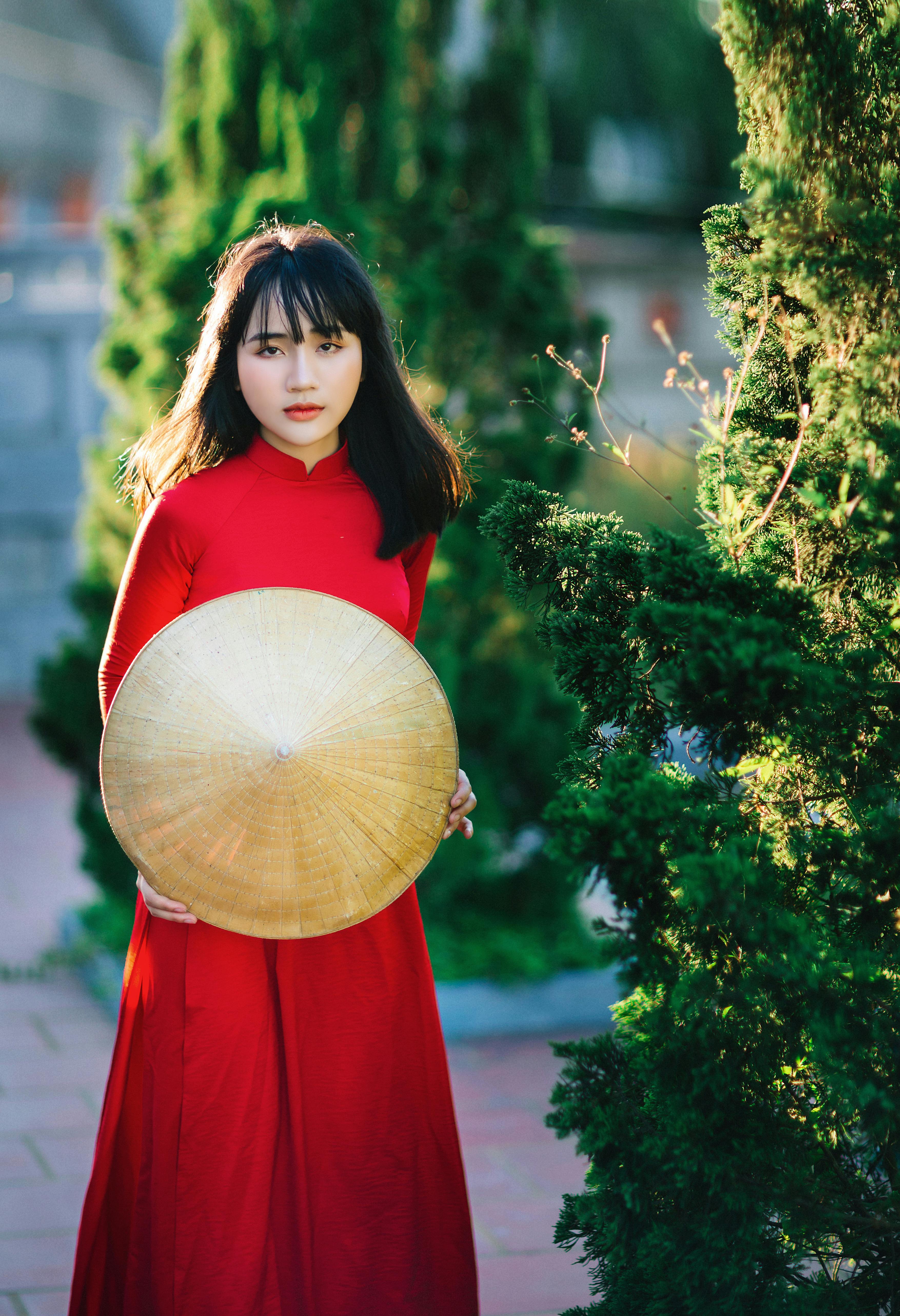 woman in a red dress holding an asian conical hat