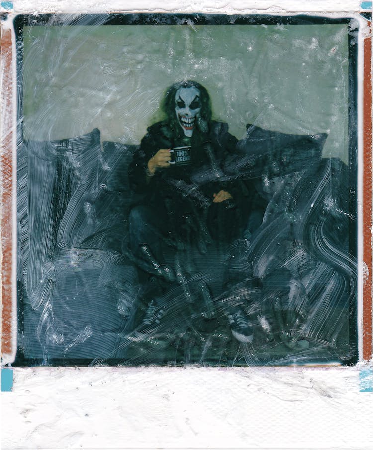 Polaroid Photo Of Man With Joker Face Sitting On Couch