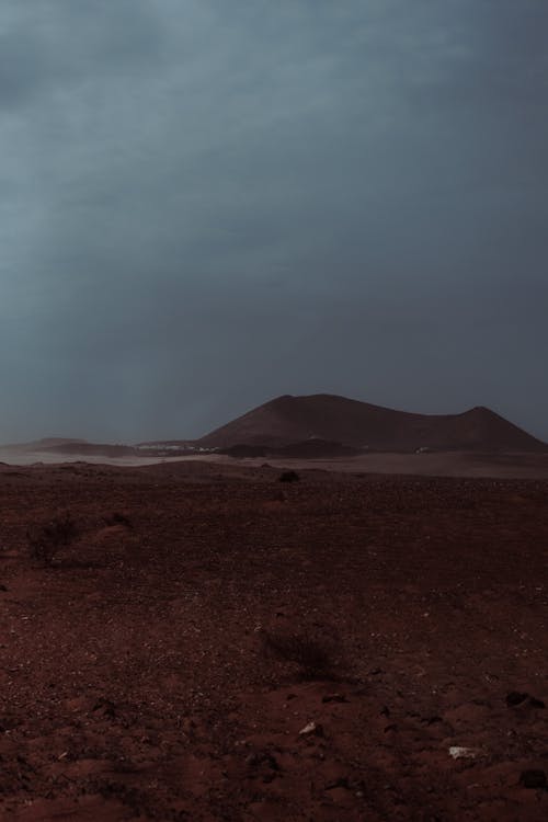 Free Brown Field Near Mountain under a Dark Sky Stock Photo