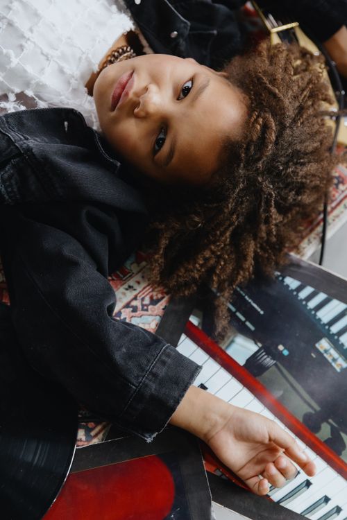 Free A stylish young girl posing with vinyl records and a keyboard in an artistic setting. Stock Photo