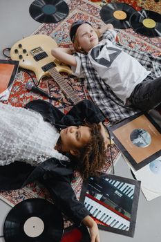 Two children enjoy a musical moment among vinyl records and a guitar.