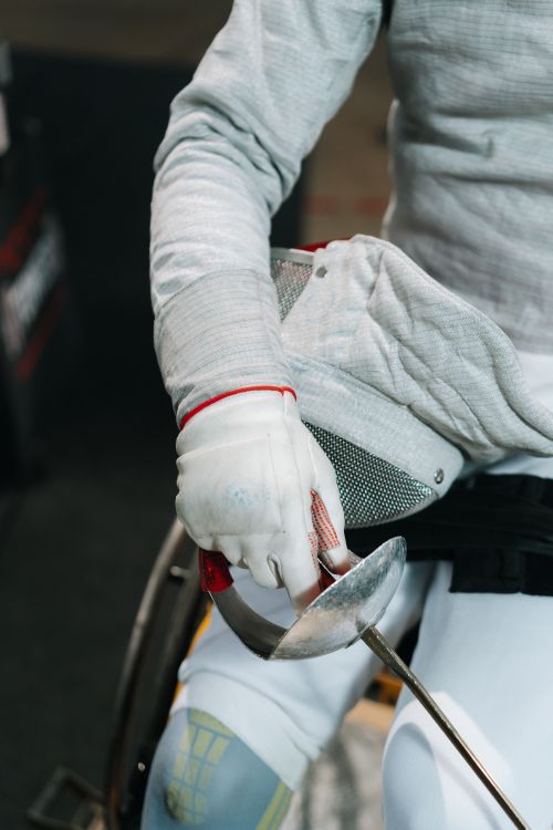 Free Focused view of a wheelchair fencer holding a sabre, preparing for a match. Stock Photo