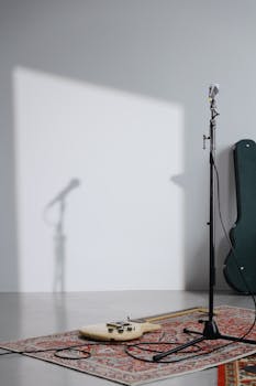 A minimalist music studio setup featuring an electric guitar and microphone stand on a patterned rug, ideal for creative projects.