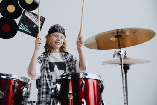 A young drummer enthusiastically playing a red drum set with vibrant energy.