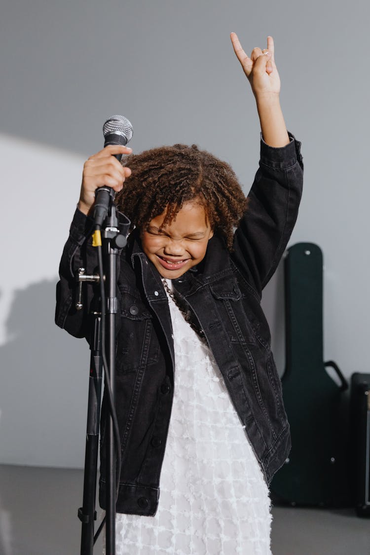 Photo Of A Child In A Black Denim Jacket Holding A Microphone