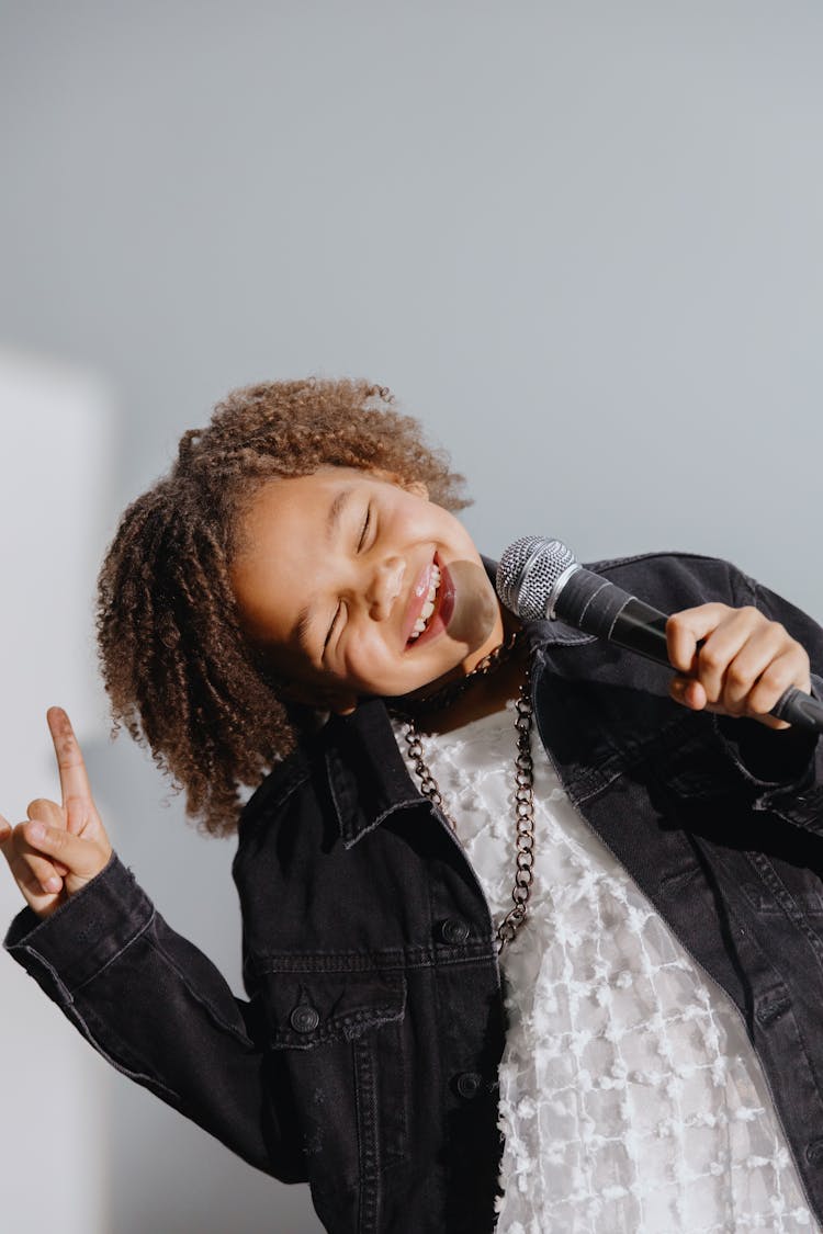 Photo Of A Kid Holding A Microphone While Her Eyes Are Closed