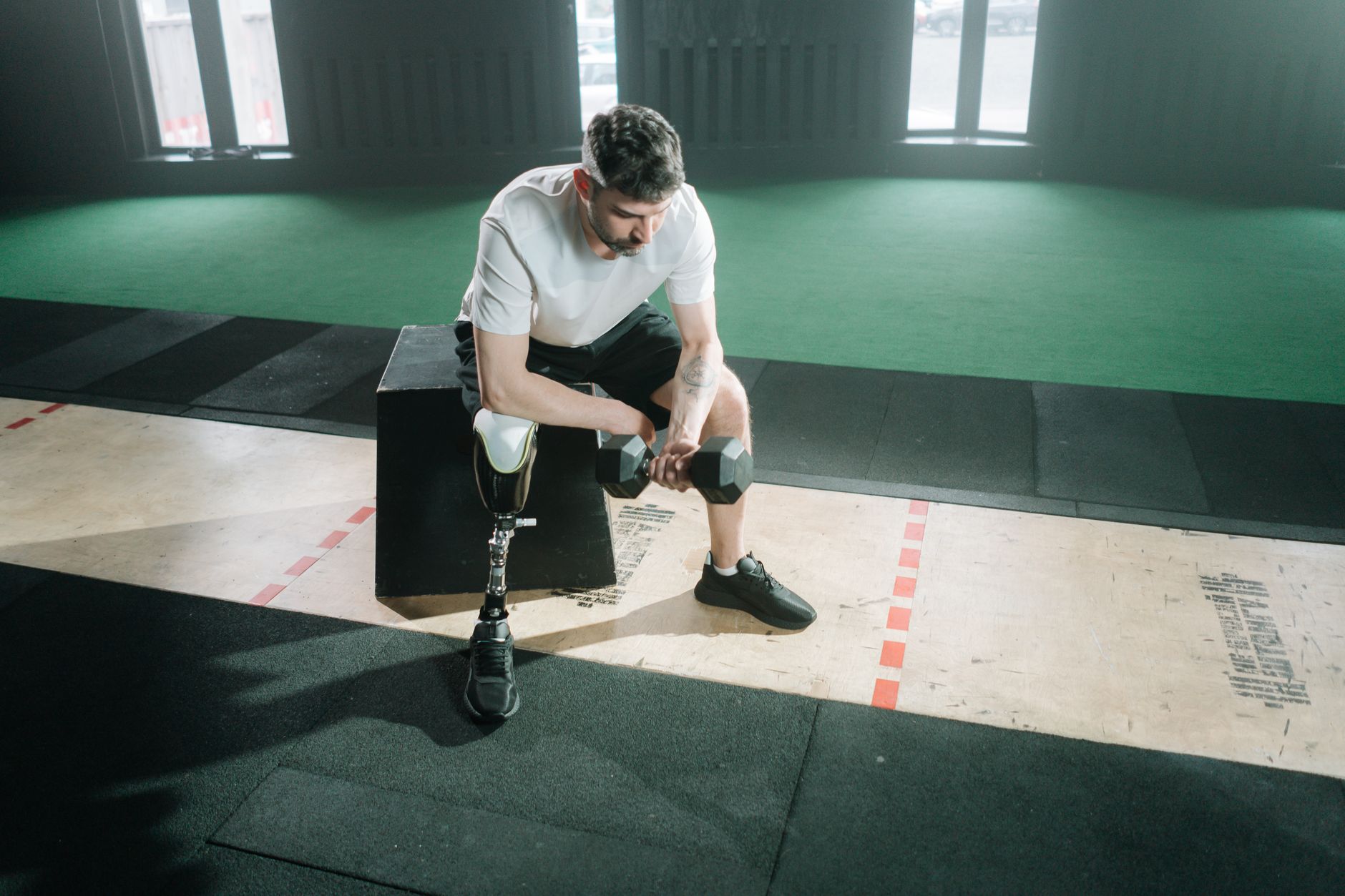 健美訓練與飲食期:心理建設實用指南 A determined athlete exercises with a dumbbell, showcasing strength and perseverance with a prosthetic leg.
