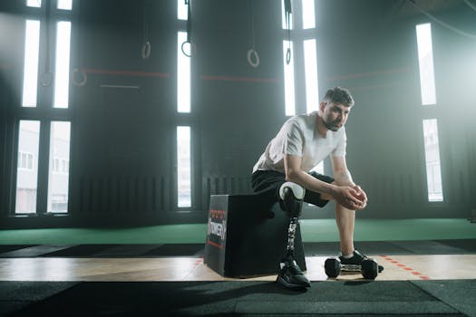 An athlete with a prosthetic leg sitting in a gym, reflecting on his workout routine. Determination and resilience.