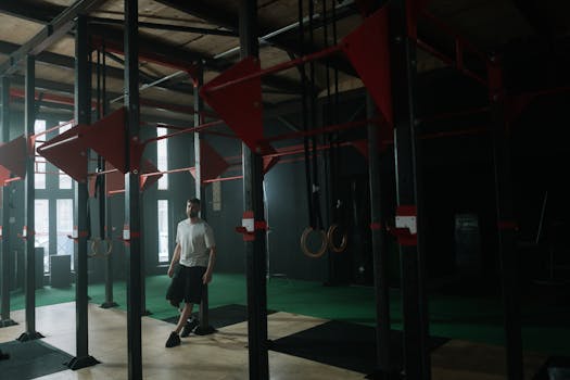 A man with a prosthetic leg trains in a dimly lit gym, leaning against exercise equipment.
