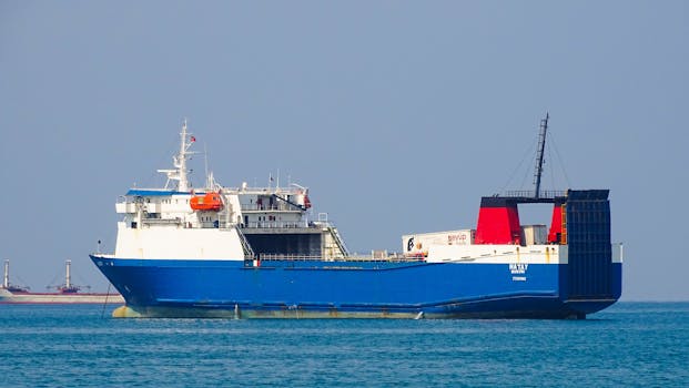 A large blue cargo ship navigating the calm ocean waters under a clear sky.