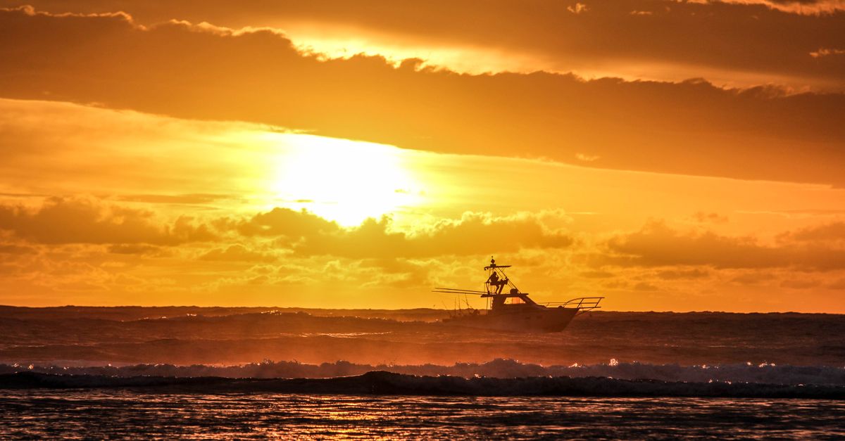 Silhouette of a fishing boat on the sea at golden hour
