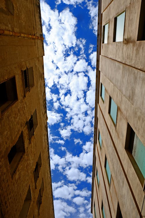 Low Angle Photography of Brown Concrete Building Under White Cloudy Blue Sky at Daytime