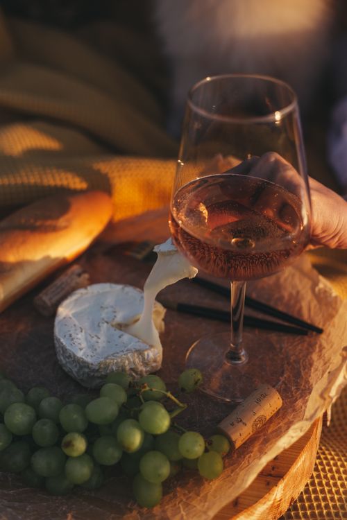 Free A serene outdoor picnic setup with wine, cheese, grapes, and natural sunlight. Stock Photo