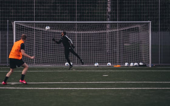 Goalkeeper jumps to save a soccer ball during an outdoor training session on an artificial turf field.