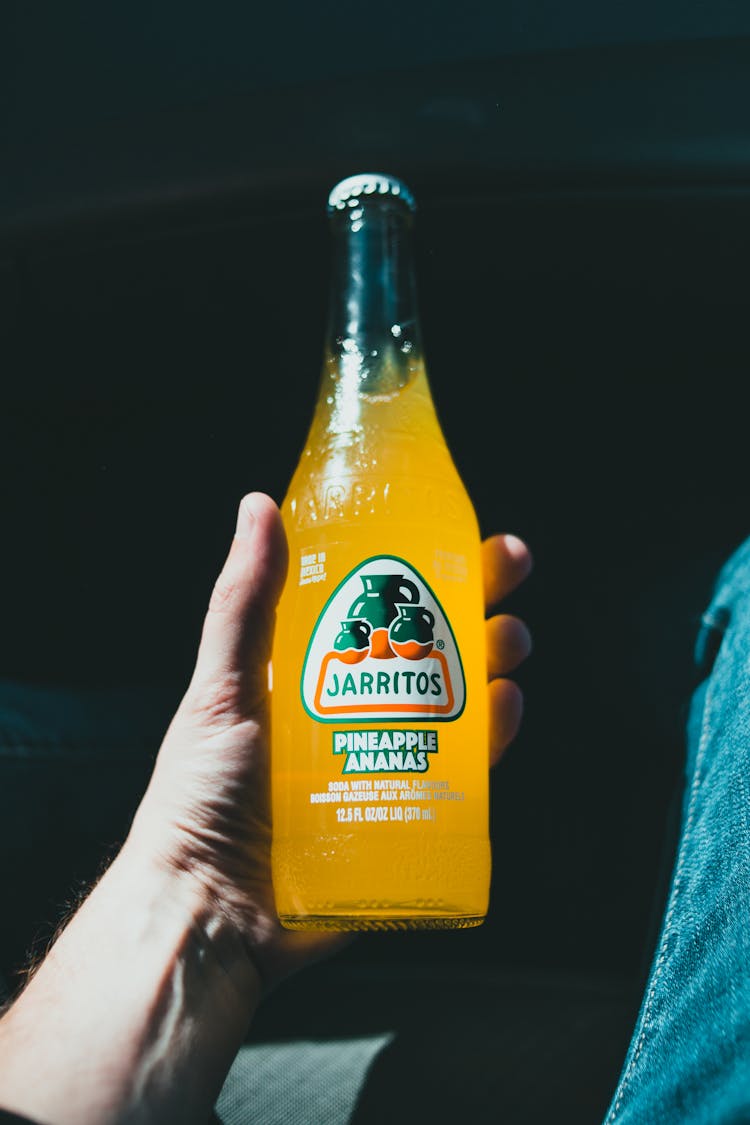 Photo Of A Person's Hand Holding A Pineapple Drink