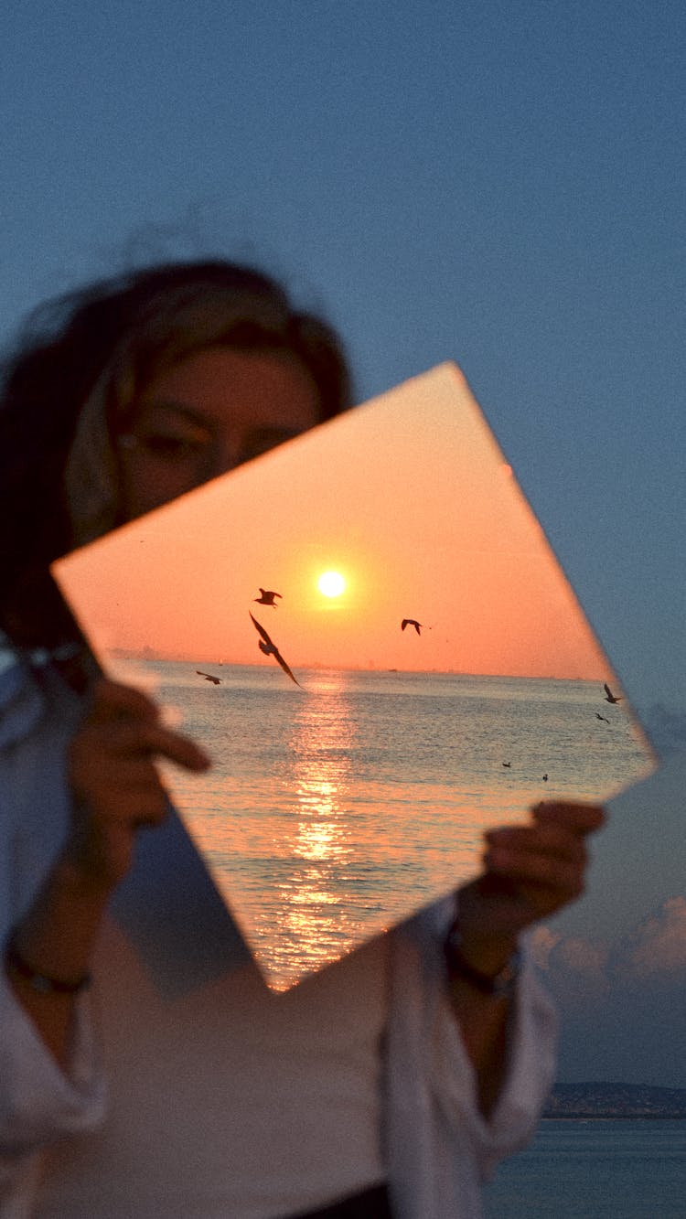 Photo Manipulation Of Woman Holding Image Of Sunset Over Sea
