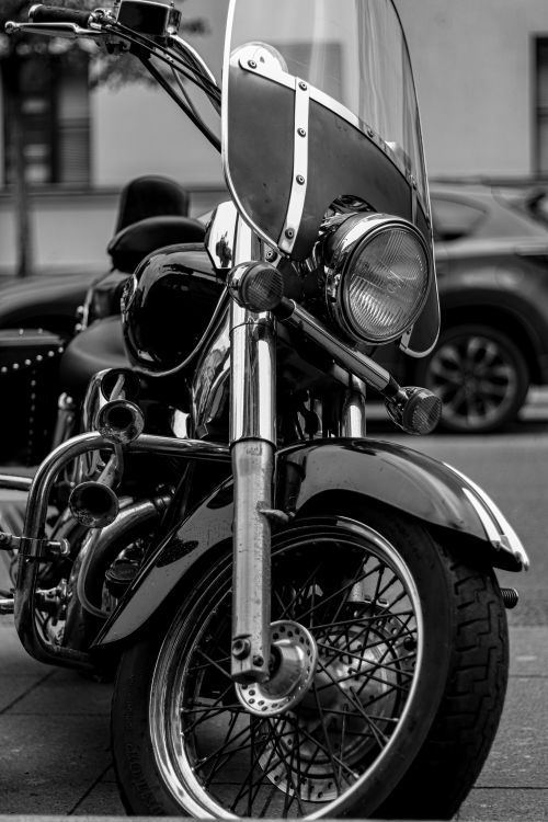 Free Black and white image of a classic motorcycle parked on a city street, emphasizing its detail and design. Stock Photo