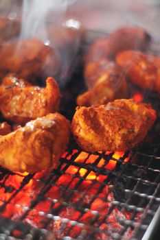 Close-up of sizzling tandoori chicken pieces on a hot grill, showcasing vibrant spices and smoky flavors.