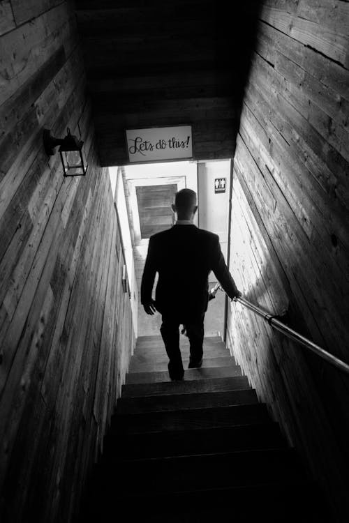 Grayscale Photo of a Man Going Down the Stairs