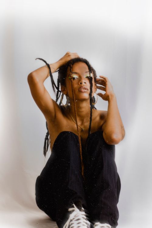 Free Captivating studio portrait of an African American woman with braided hair, seated against a white background. Stock Photo
