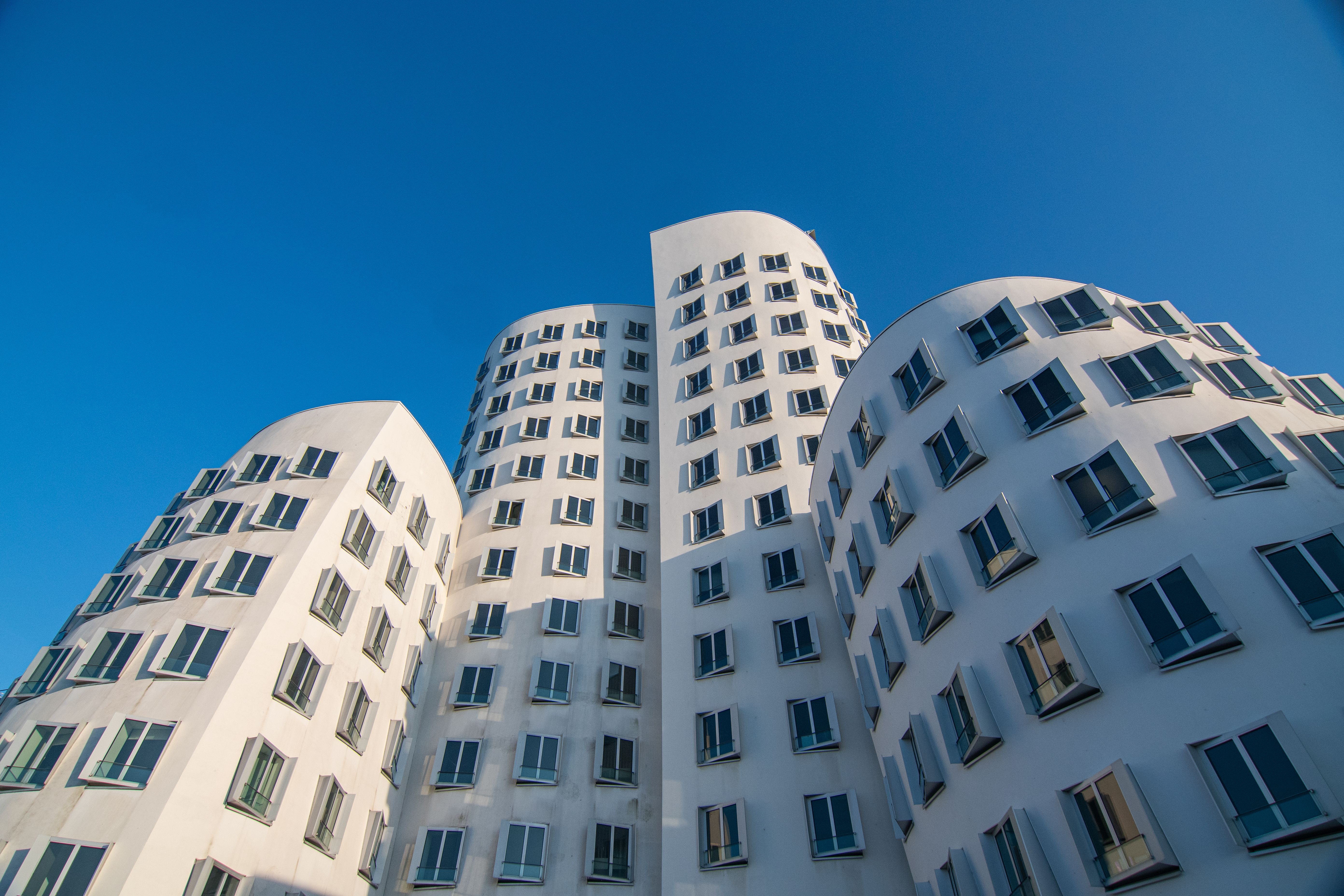 Stunning view of the Gehry Buildings in Düsseldorf's MedienHafen under a clear blue sky.