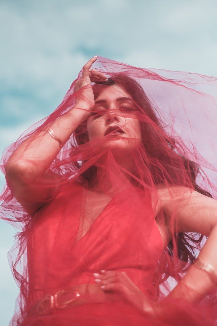 Woman Posing In Red Halter Dress And Veil Covering Her Face