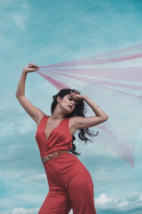 A Woman in a Red Halterneck Jumpsuit Holding a Fabric