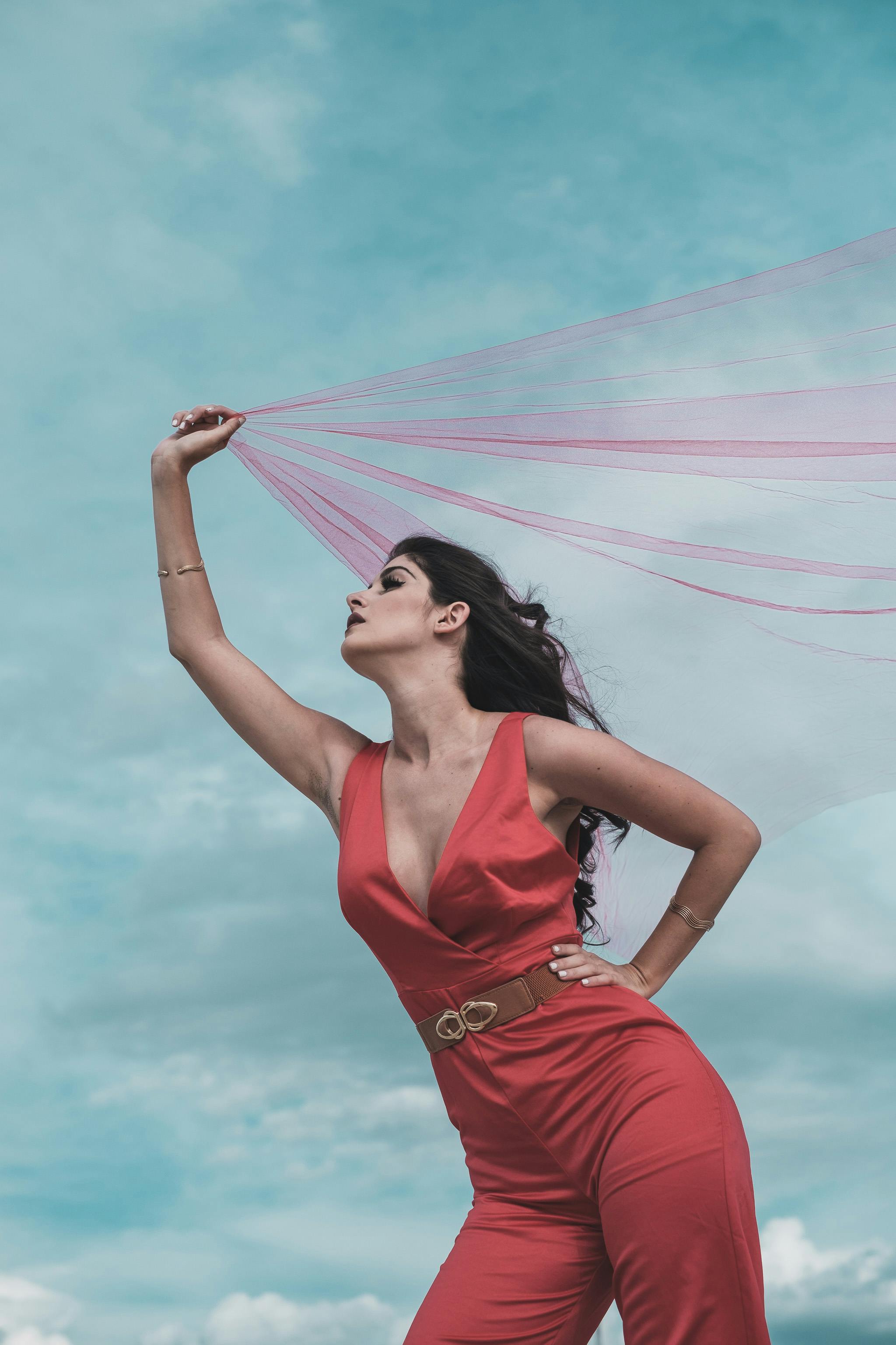 woman in red jumpsuit holding a red tulle