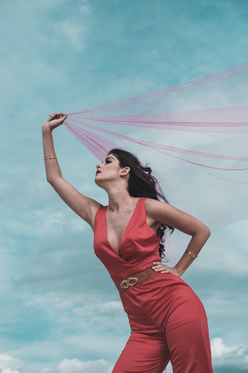 Free Woman in Red Jumpsuit Holding a Red Tulle Stock Photo