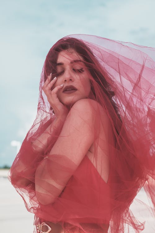 Woman Posing with a Red Sheer Fabric