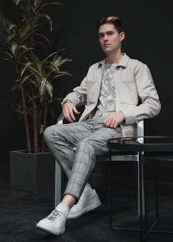 Portrait of a fashionable young man seated indoors, showcasing modern style.