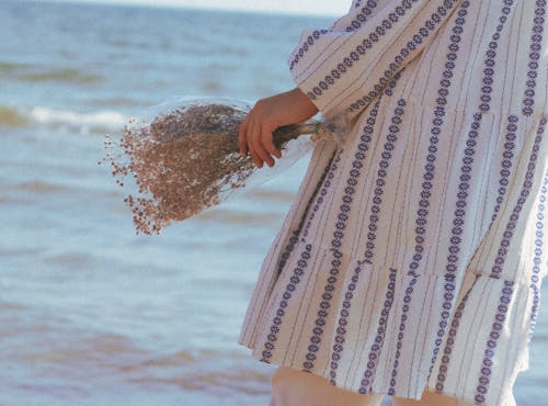 Woman Holding Flowers with Water in Background