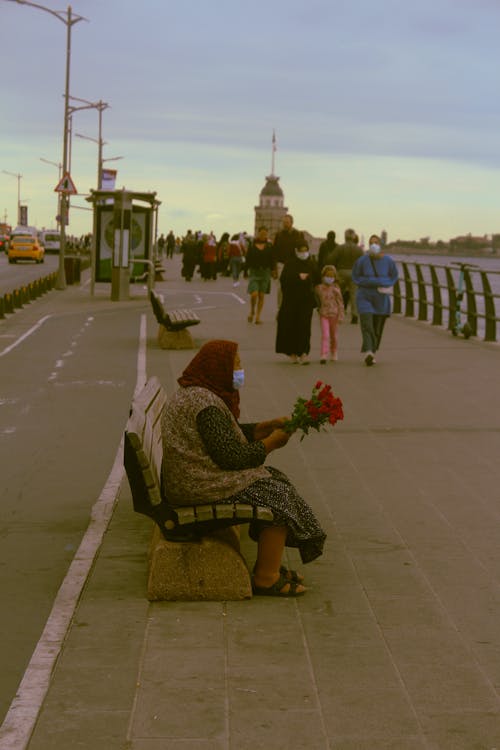 Woman Sitting on Bench Holding Red Roses