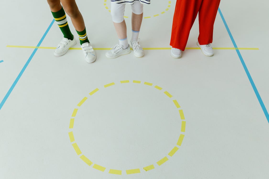 Free Kids Wearing White Sneakers Standing Near the Yellow Circle  Stock Photo