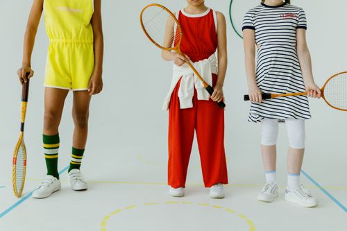 Free Three children holding rackets, showcasing colorful sportswear on an indoor court. Stock Photo