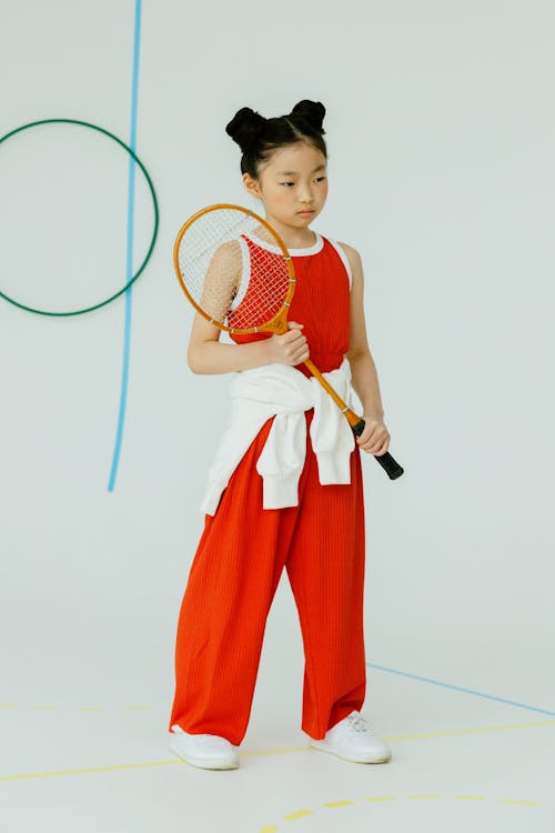 Girl in Red and White Tank Top and Red Pants Holding White and Badminton Racket