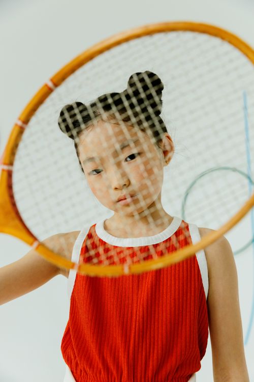 Free A young girl wearing a red top holding a tennis racket. Perfect for sports and lifestyle themes. Stock Photo