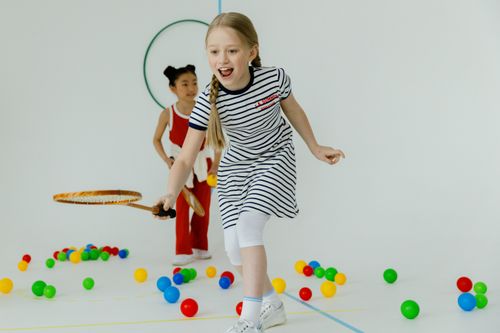 Free Two girls having fun playing indoors with rackets and colorful balls, full of joy. Stock Photo