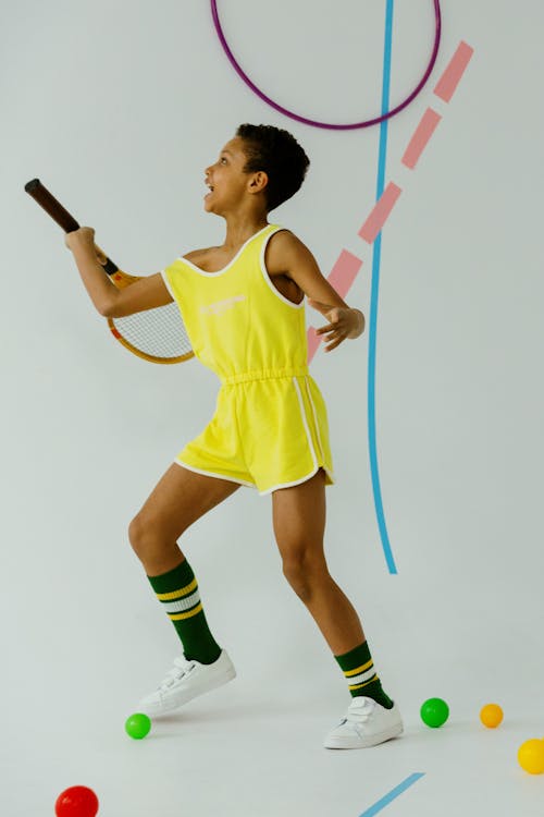 Free Woman in Yellow Nike Tank Top and Green Shorts Holding Black and White Stick Stock Photo