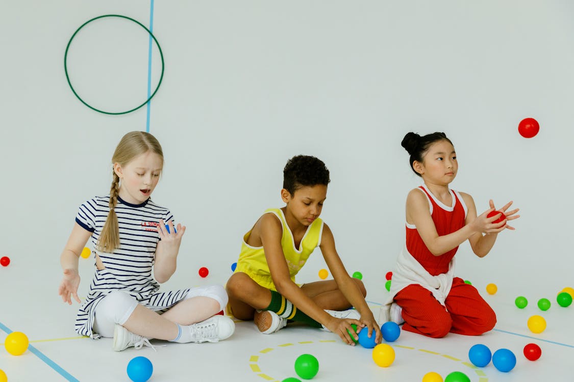 Free Girls Sitting on the Floor Playing Colorful Balls Stock Photo