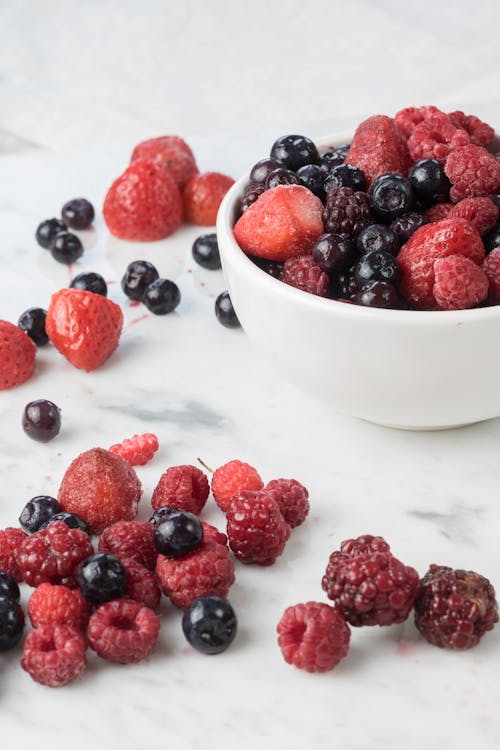 Raspberries and Blueberries in White Ceramic Bowl