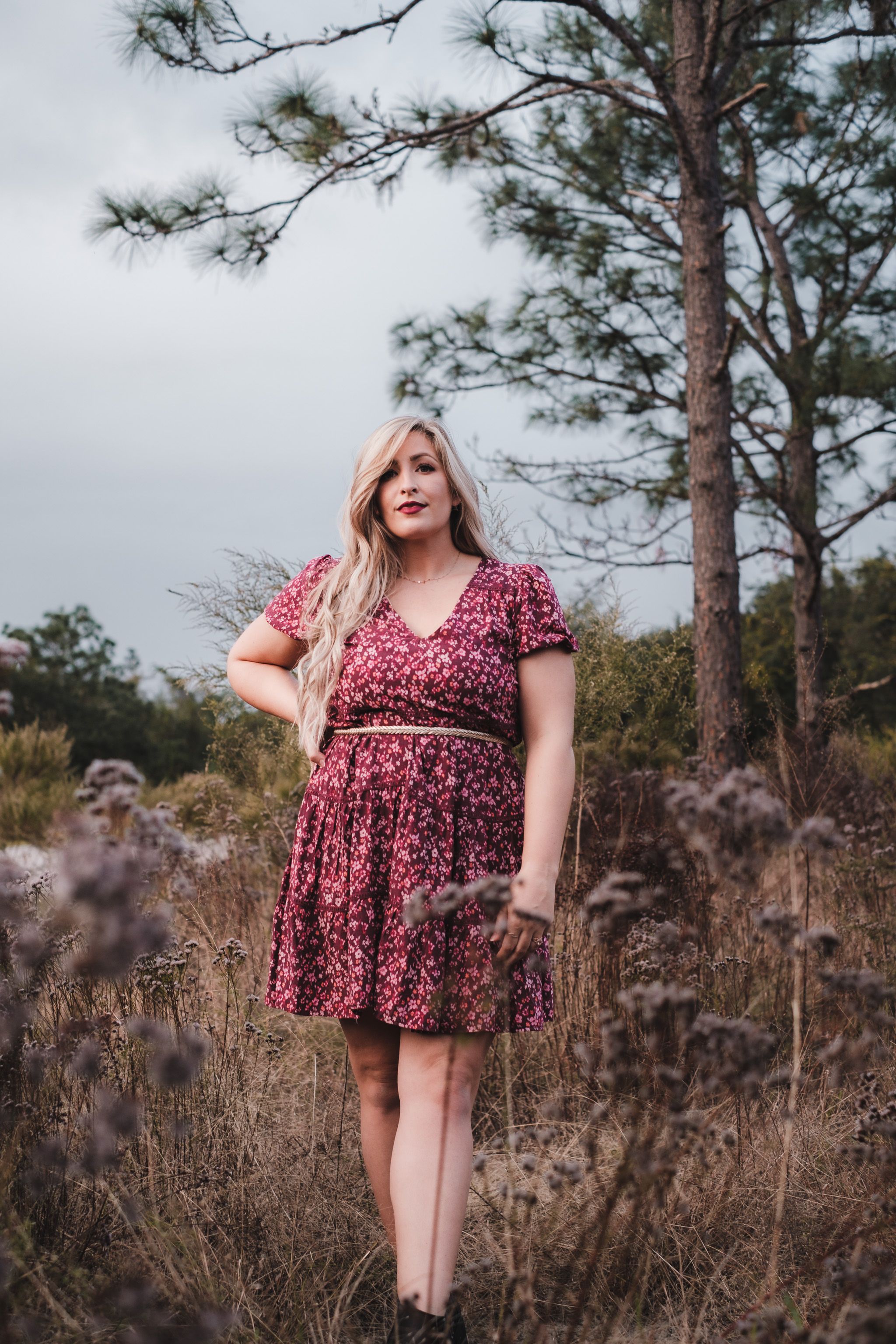 Woman in Red Floral Dress Standing on Brown Grass Field · Free Stock Photo