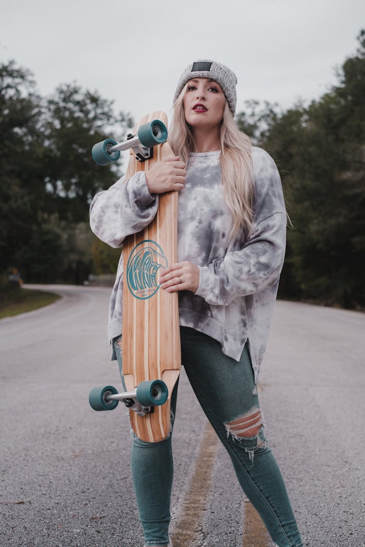 A Woman In A Sweater Holding Her Longboard