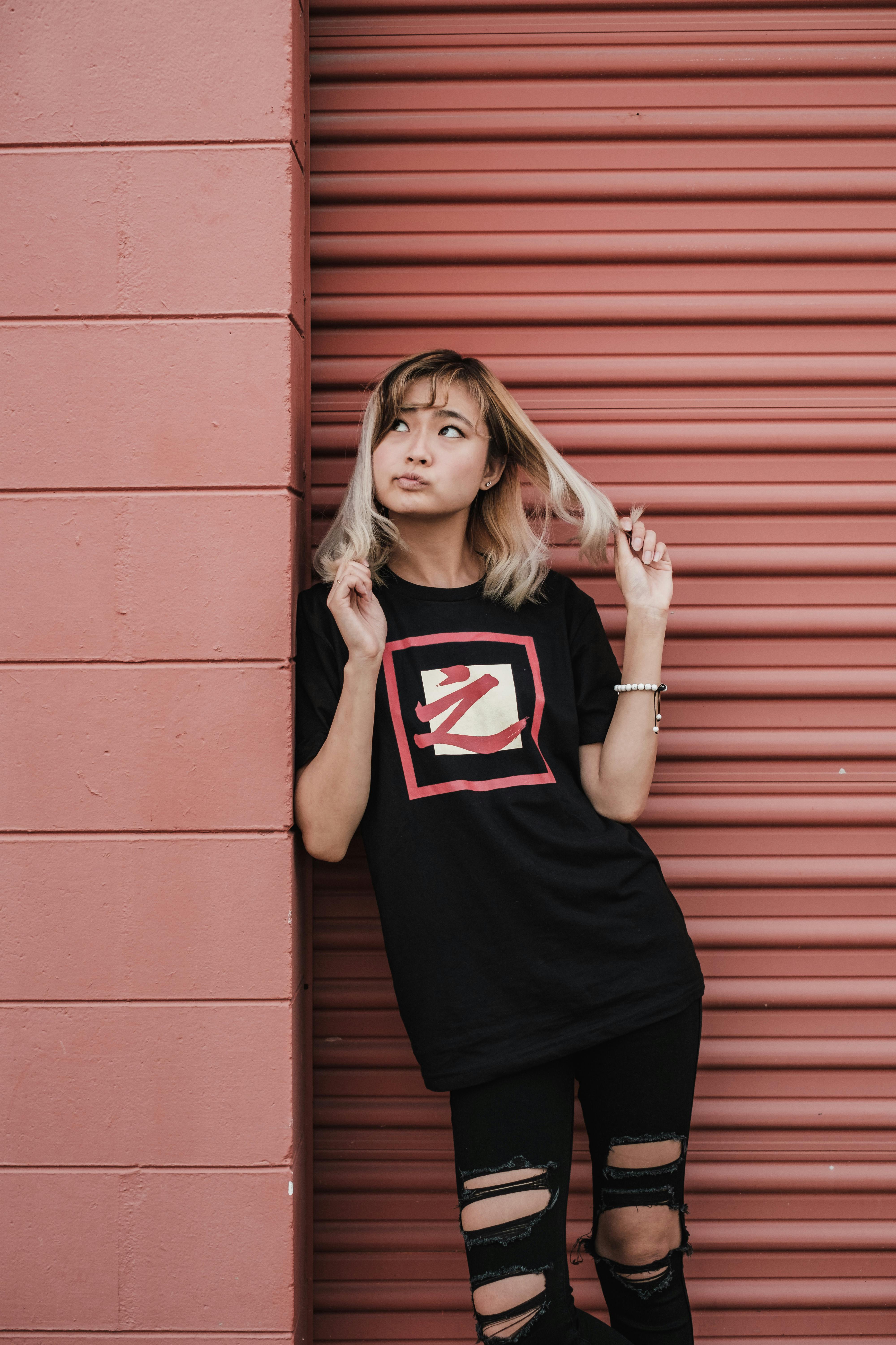 woman leaning against wall playing with hair