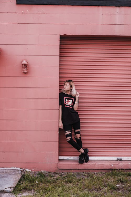 Free Girl in Black Shirt Leaning on Red Wall Stock Photo
